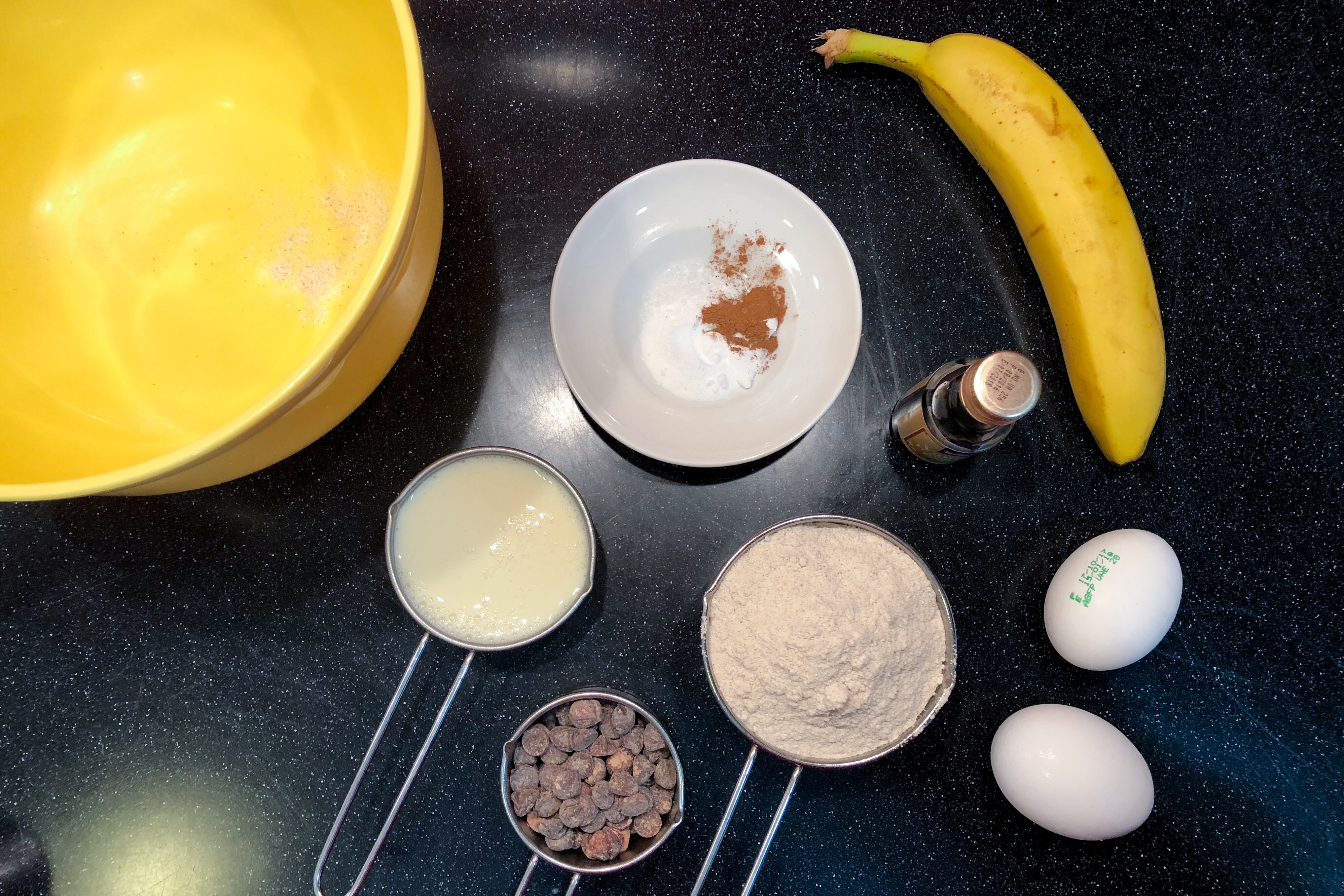 ingredients for gluten free banana pancakes shown banana chocolate chips eggs buckwheat flour and soy milk
